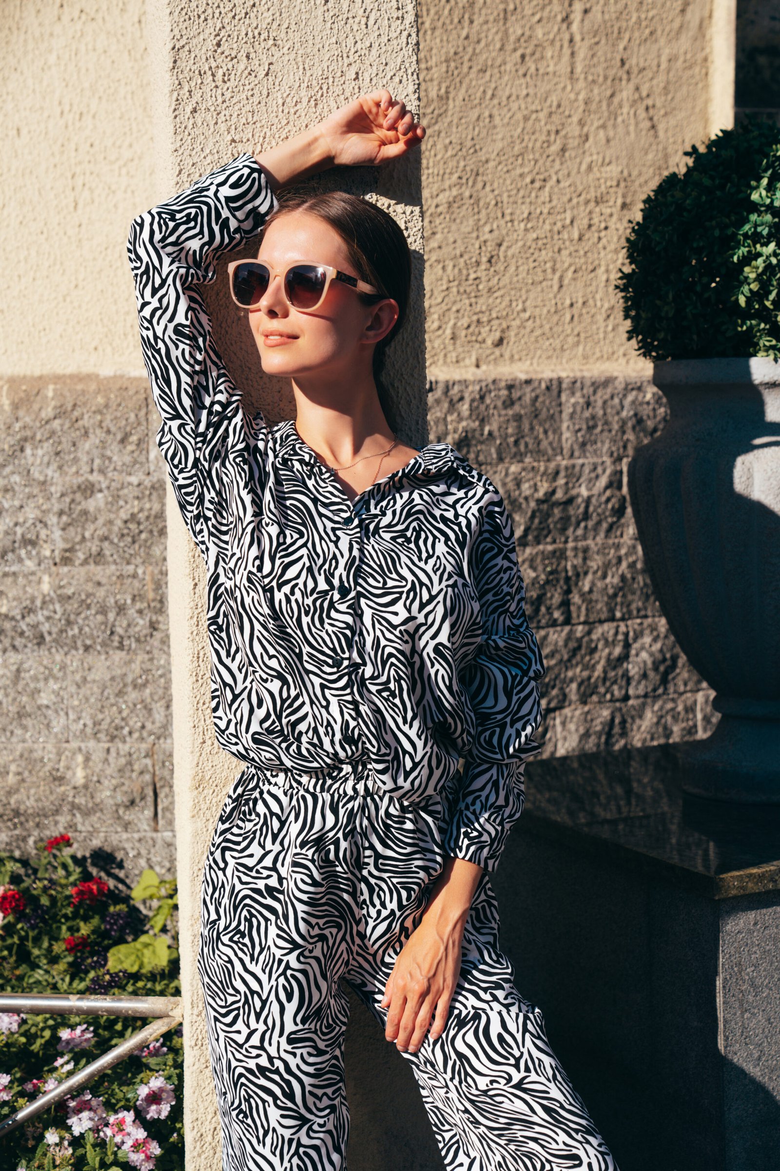 Young beautiful smiling hipster woman in trendy summer zebra print costume clothes. Carefree model posing in the street at sunset. Positive blond female. Cheerful and happy. In sunglasses